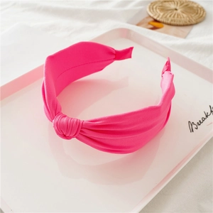 Close-up of knotted rose red headband with textured fabric on a decorative tray