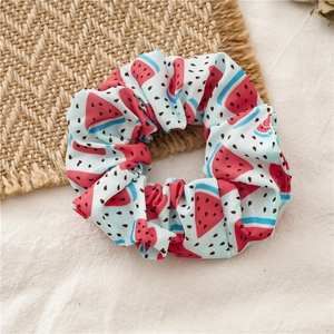 Detailed view of handmade watermelon pattern scrunchie hair tie on a rustic straw mat