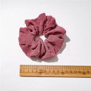 Solid pink seersucker scrunchie with textured polka dots and 11cm diameter measurement