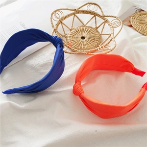 Cross-knotted wide fabric headbands in vibrant navy blue and bright orange colors