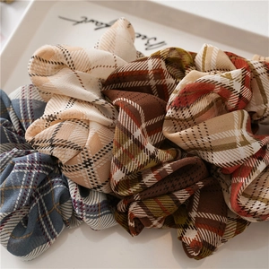 Détail de motifs à carreaux sur chouchous en tissu doux présentés dans un plateau blanc