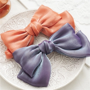 Détails de la texture nacrée des nœuds papillon pour cheveux en violet et orange