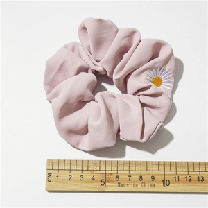 Elastico per capelli in raso rosa pallido con ricamo a margherita su sfondo bianco