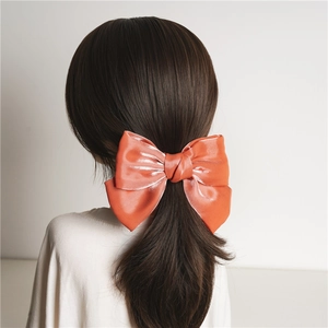 Détail du nœud papillon en satin orange corail avec texture soie lisse et fini brillant