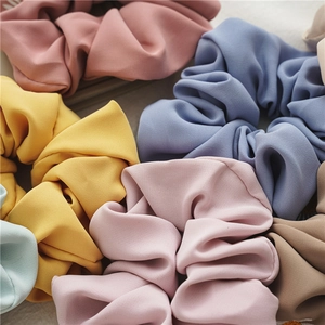 Dettaglio di scrunchies in raso pastello con eleganti ricami floreali a margherita