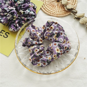 Dettaglio di elastici per capelli floreali in chiffon viola in un piatto di vetro