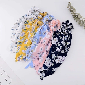 Flat lay of five floral print scrunchies with ribbons in various pastel colors