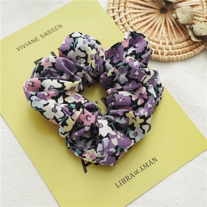 Dettaglio del motivo floreale viola e della trama del morbido tessuto dello scrunchie