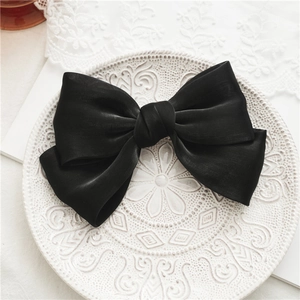 Détail d'un grand nœud papillon en satin noir sur une assiette en dentelle vintage