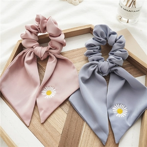 Détail de chouchous en satin avec broderie marguerite en rose poudré et bleu brume