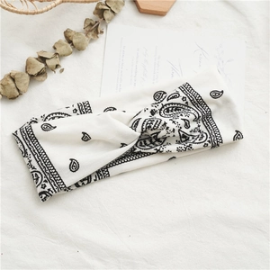 Detail shot of a white paisley twist headband on a minimalist aesthetic background