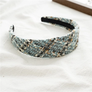 Close-up of luxury tweed headband featuring light blue and beige woven texture
