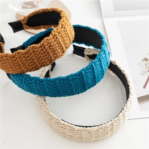 Detailed close-up of knitted headbands in mustard yellow, cyan blue and beige textures