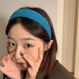 Detail of teal knit headband with ribbed texture worn by a model in casual setting