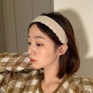 Detail of chunky beige knitted headband worn by model showing thick wool texture