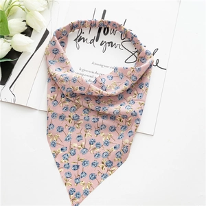Detail view of pink floral hair scarf with blue flowers and elastic band on a magazine