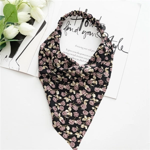 Detailed close-up of floral headscarf with purple rose pattern on black fabric backdrop