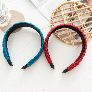 Detail showing hand-knit texture of navy and red winter headbands on wood tray