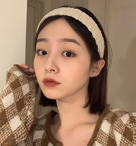 Close-up of a beige knitted headband featuring a vertical stripe texture on a model