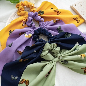 Close-up of four floral chiffon hair scrunchies with long ribbons and butterfly patterns