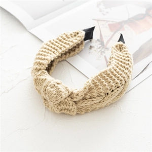 Détail d'un bandeau en maille épaisse beige avec nœud et texture tressée douce