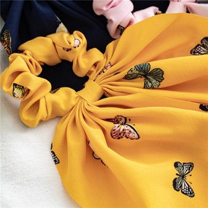 Close-up of yellow chiffon hair scrunchie with elegant black and green butterfly patterns