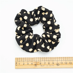 Polka dot fabric scrunchie in black and white with a ruler showing a 9cm outer diameter size