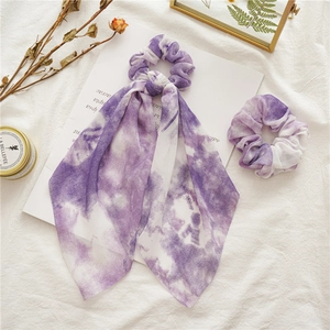 Detailed view of purple tie-dye hair scrunchies set with long ribbon on white fabric