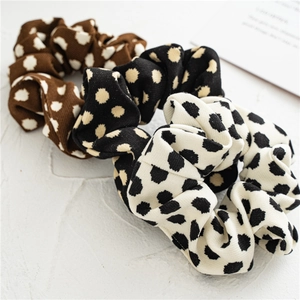 Close-up of three knitted polka dot scrunchies in brown, black, and white textures