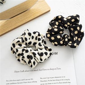 Spotted fabric hair scrunchies with classic polka dot pattern in black and white colors
