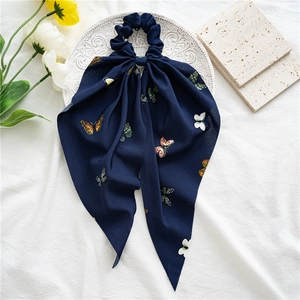 Detail of navy blue chiffon scrunchie with colorful butterfly print on white tray