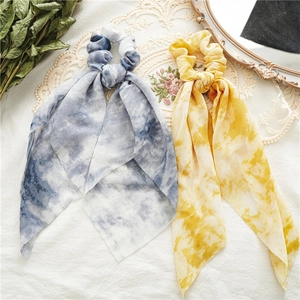 Flat lay detail of tie-dye chiffon scrunchies with streamers in blue and yellow colors