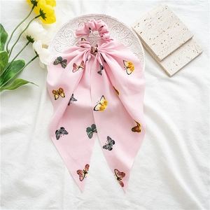 Pink chiffon scrunchie with butterfly print and long ribbon bow on white textured fabric