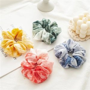Dettaglio di quattro elastici per capelli in chiffon tie-dye su una scrivania bianca