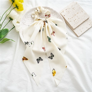 Detail view of cream chiffon hair scrunchie with colorful butterfly prints on fabric