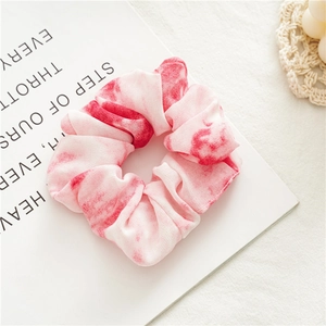 Dettaglio ravvicinato di un elastico per capelli in chiffon tie-dye rosa e bianco