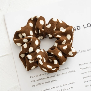 Macro detail of brown polka dot fabric scrunchie with fine ribbed texture and soft folds