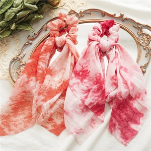 Detailed view of tie-dye silk ribbon scrunchies placed on a vintage golden mirror