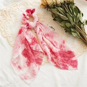 Detail of pink and white tie-dye silk scrunchie with streamers on vintage lace cloth