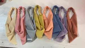 Flat lay of eight colorful elastic headscarves in soft fabric on white wood background