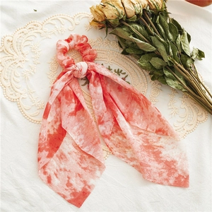 Detail of red and white tie-dye chiffon hair scrunchie with long ribbons on lace background
