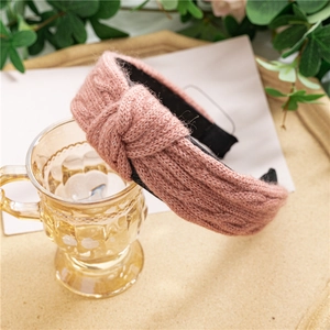 Détail du bandeau en tricot rose avec motif torsadé et nœud croisé tendance