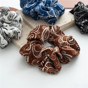 Close-up of four paisley print hair scrunchies in brown, white, blue, and black fabrics