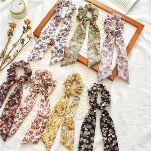 Floral fabric scrunchies with long ribbons in seven vintage colors on a white tablecloth