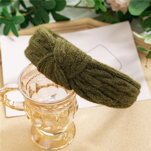 Gros plan du bandeau tricoté vert foncé avec des détails de nœuds et textures tressées