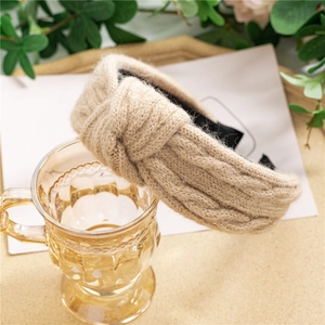 Détail de la maille d'un bandeau à nœud beige drapé sur un verre élégant