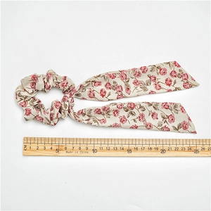 Floral hair scrunchie with pink rose print and long ribbons for elegant ponytail styling