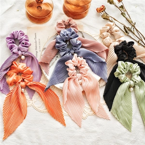 Detailed shot of pleated satin scrunchies with long ribbons and elegant pearl charms