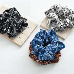 Detail view of retro paisley pattern scrunchies on a textured beige stone display board