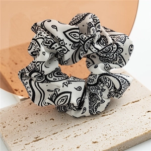 Detail shot of vintage paisley print scrunchie in beige and black on a textured stone board